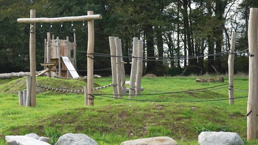 Climbing play equipment which is framing a woods tower with a slide in the background